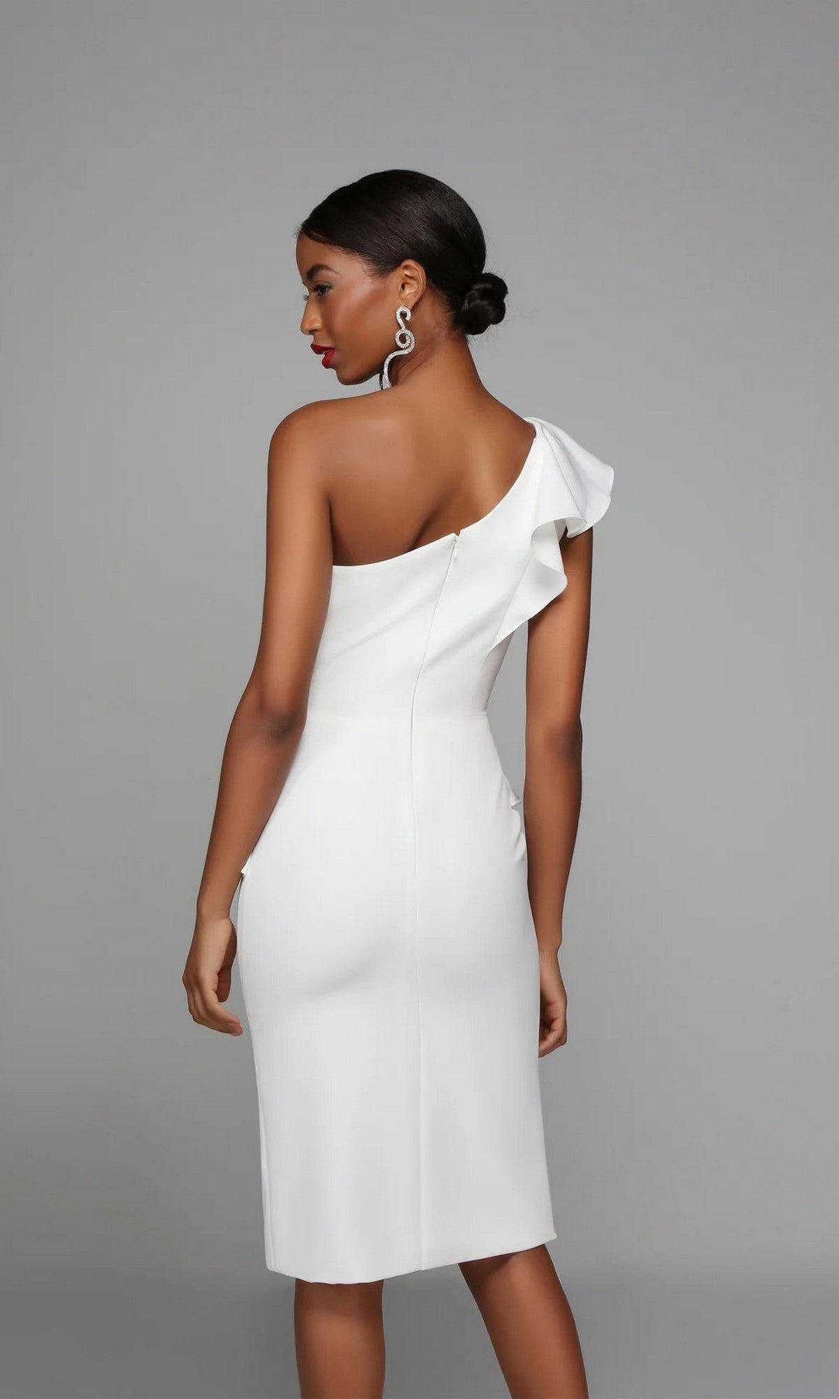 A woman in the Alyce 70007 knee-length white party dress stands against a plain gray background, facing away from the camera.